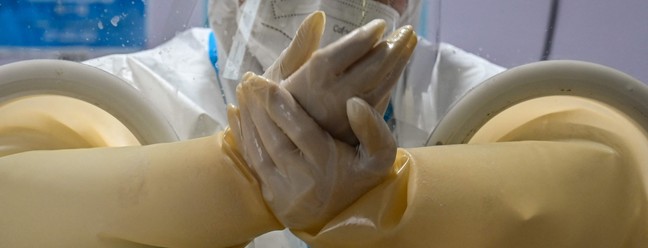 Profissional de saúde se prepara para colher uma amostra de swab de uma pessoa para teste de Covid-19, em Xangai, China — Foto: HECTOR RETAMAL/AFP