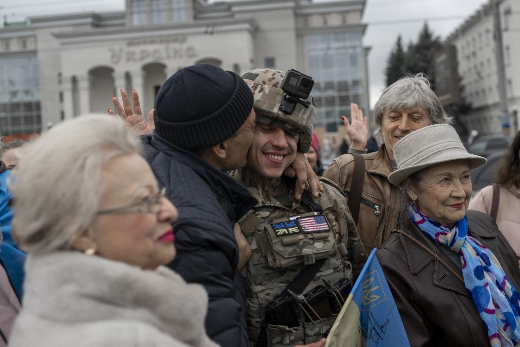 Foto de 13 de novembro de 2022 mostra um homem abraçando um soldado ucraniano enquanto os moradores locais celebram a libertação de Kherson.  — Foto: Bulent KILIC / AFP