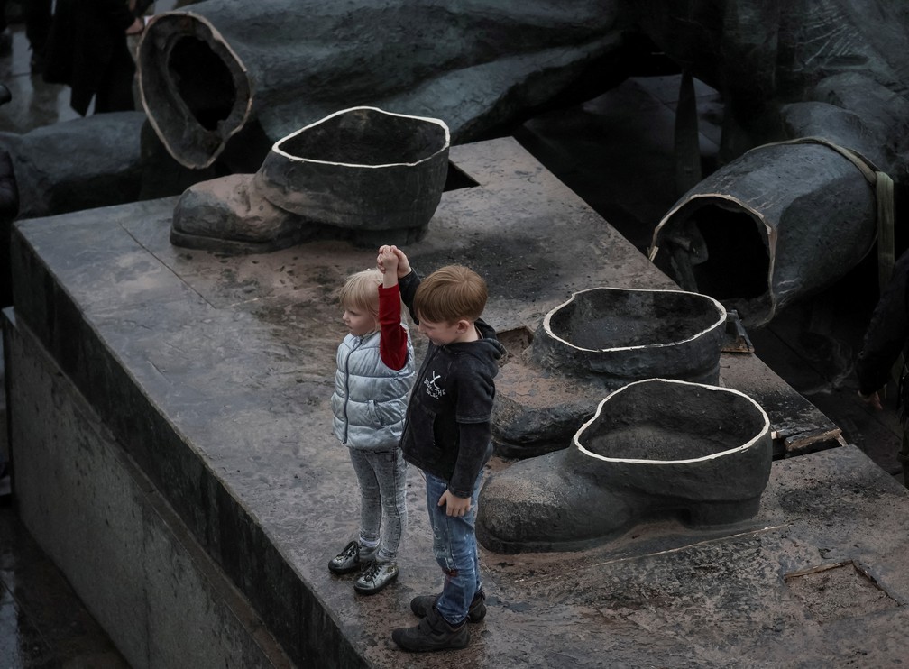 Crianças brincam no local onde estátua que comemorava a amizade russo-ucraniana foi removida em Kiev — Foto: Gleb Garanich/Reuters