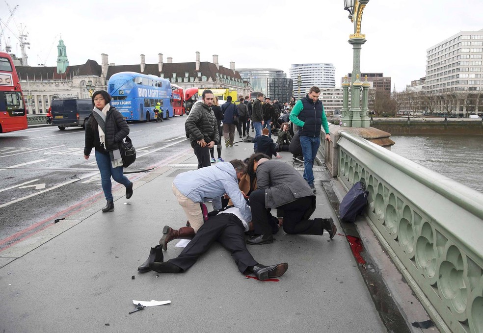 Pessoas ajudam homem que foi ferido em ataque perto do Parlamento, em Londres (Foto: Toby Melville/Reuters)