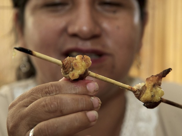 Mulher come larva no espeto no Equador (Foto: Reuters/Guillermo Granja)
