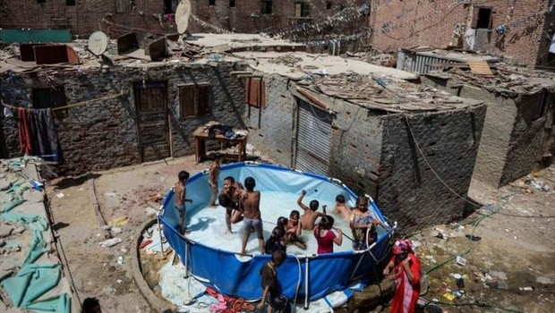Crianças brincando em piscina de plástico (Foto: EPA via BBC)