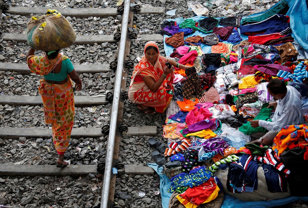 Uma mulher faz compras ao lado de uma linha de trem em Kolkata, na Índia (Foto: Rupak De Chowdhuri/Reuters)
