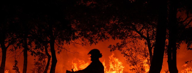 Bombeiro combate incêndio noturno em Saumos, perto de Bordeaux, sudoeste da França, onde moradores precisaram ser evacuados  — Foto: PHILIPPE LOPEZ / AFP