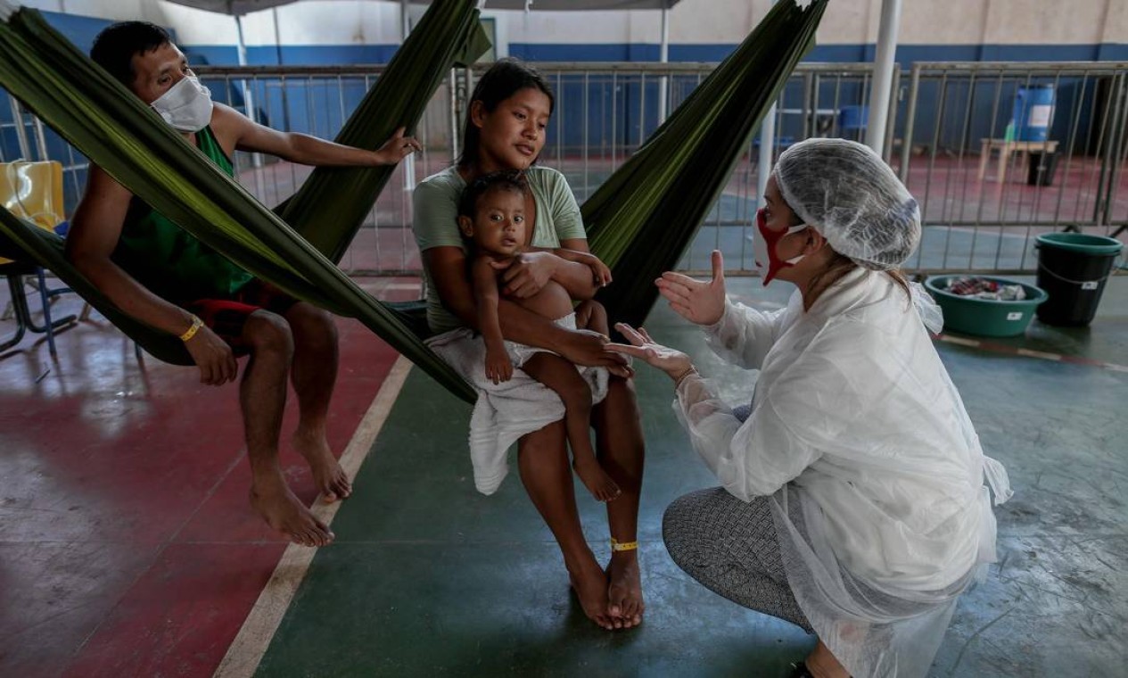 Membro do Médicos Sem Fronteiras olha para um garoto da tribo Warao, o segundo maior grupo indígena da Venezuela, que sofre de sintomas do novo coronavírus, em Manaus, no Amazonas — Foto: MICHAEL DANTAS / AFP