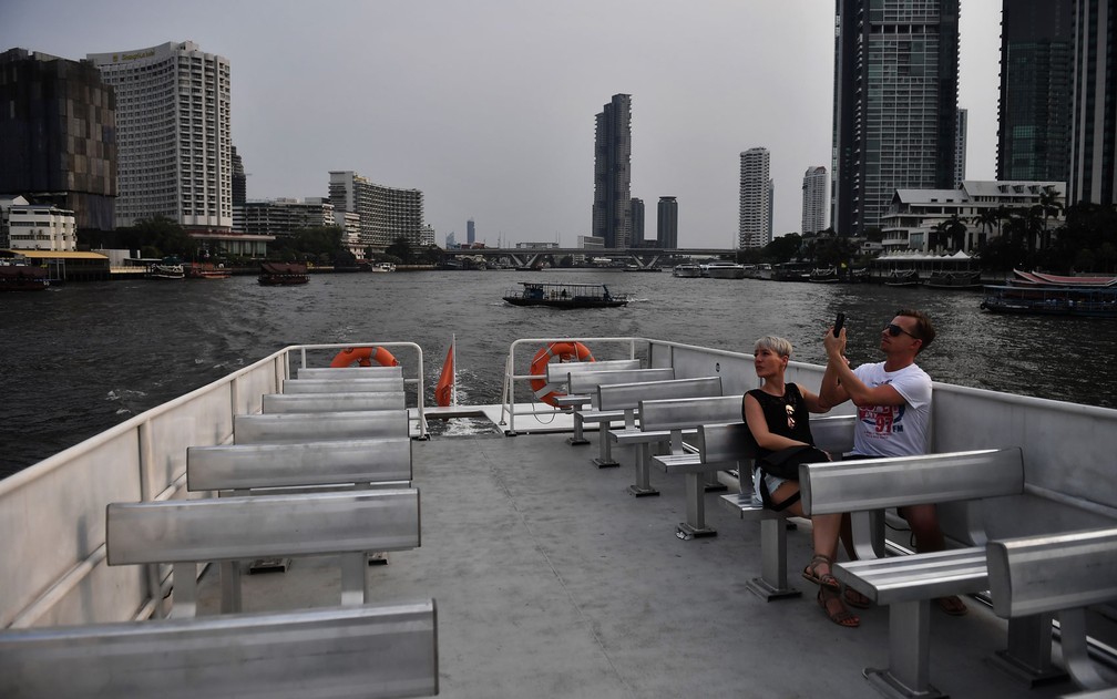 Um casal anda de barco em um passeio turístico no rio Chao Phraya em Bangkok, Tailândia, onde o número de visitantes caiu drasticamente  — Foto: Lillian Suwanrumpha/AFP