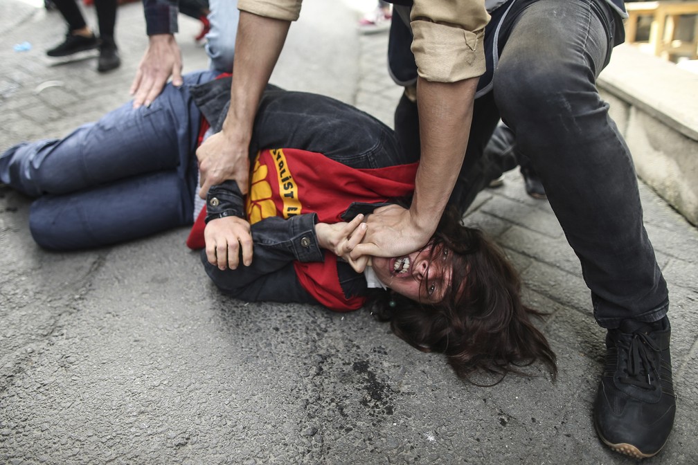Agente da Turquia imobiliza uma manifestante que tentou atravessar a barricada da polícia durante as manifestações no dia 1º de maio de 2021 — Foto: Emrah Gurel/AP