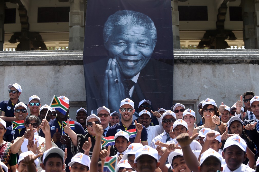 Equipe de críquete da África do Sul posa para foto nesta quarta-feira (18) com estudantes em cerimônia de homenagem aos 100 anos do nascimento de Nelson Madela (Foto: Ishara S. Kodikara/AFP)