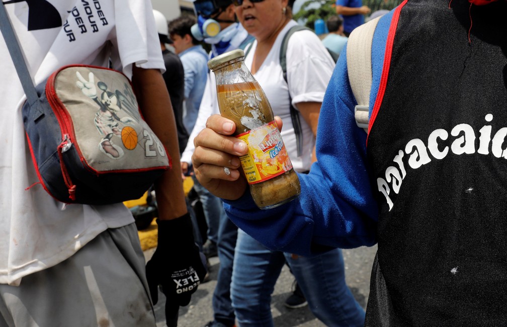 Manifestante carrega bomba de excremento, 'cocôtov', durante manifestação contra Nicolás Maduro nesta quarta-feira (10) em Caracas (Foto: REUTERS/Carlos Garcia Rawlins)