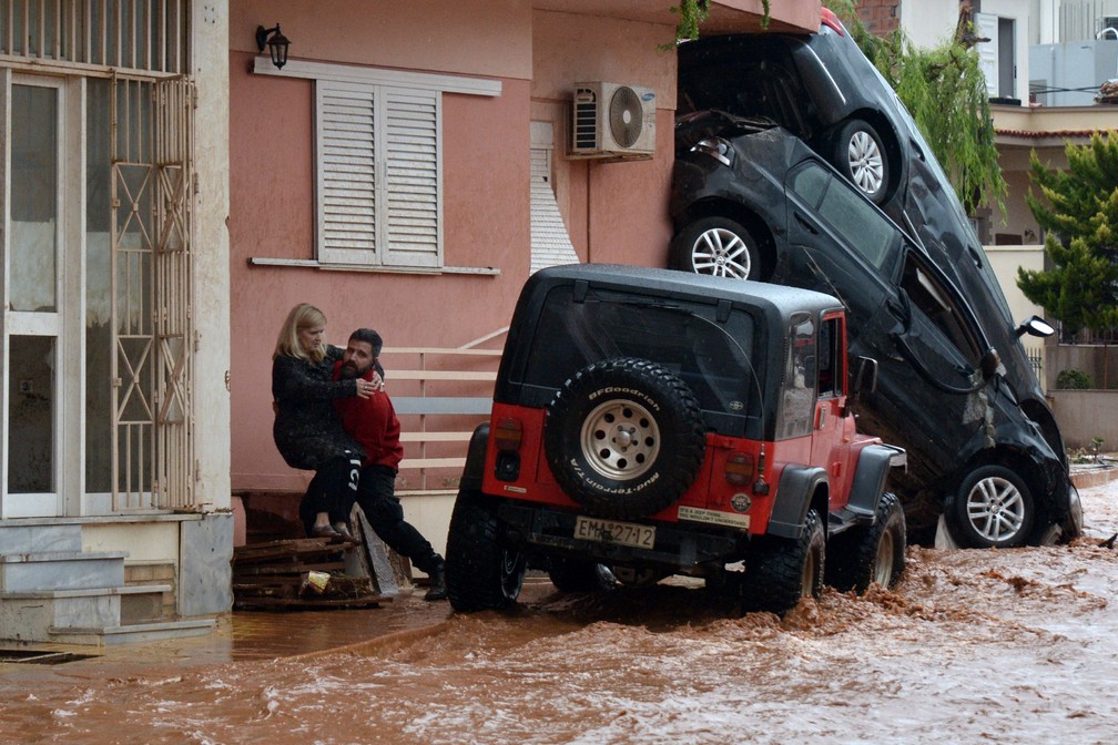 Um homem ajuda a resgatar uma mulher de uma rua inundada em Mandra, no noroeste de Atenas, na Grécia. O primeiro-ministro grego Alexis Tsipras declarou um estado de luto depois de uma forte tempestade inundou três cidades perto de Atenas, matando pelo menos 15 pessoas (Foto: Dimitris Lambropoulos/AFP)