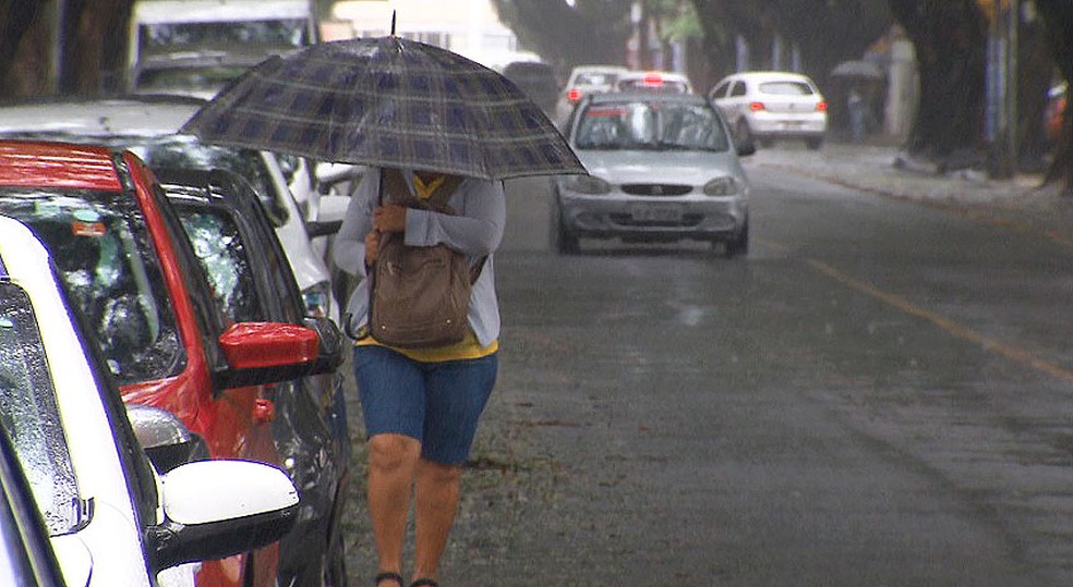 Mulher caminha e tenta se proteger da chuva nesta manhã de domingo, no centro de Salvador (Foto: Reprodução/TV Bahia)
