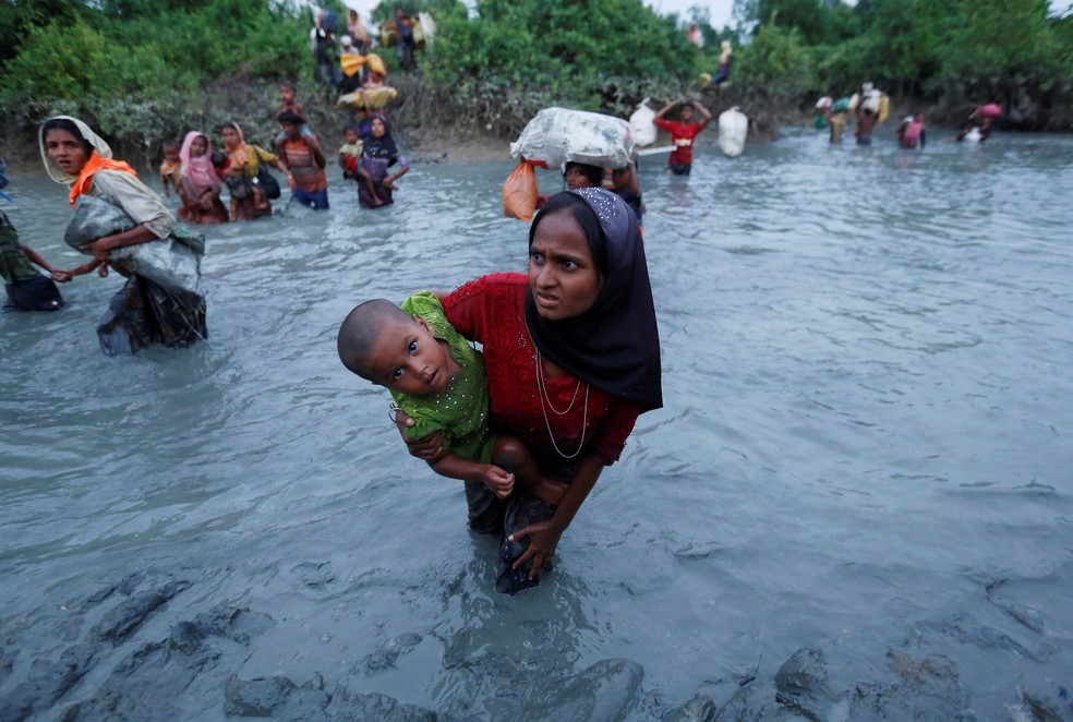 Mulher rohingya atravessa rio segurando seu filho na fronteira entre Myanmar e Bangladesh, perto de Cox’s Bazar (Foto: Adnan Abidi/Reuters)