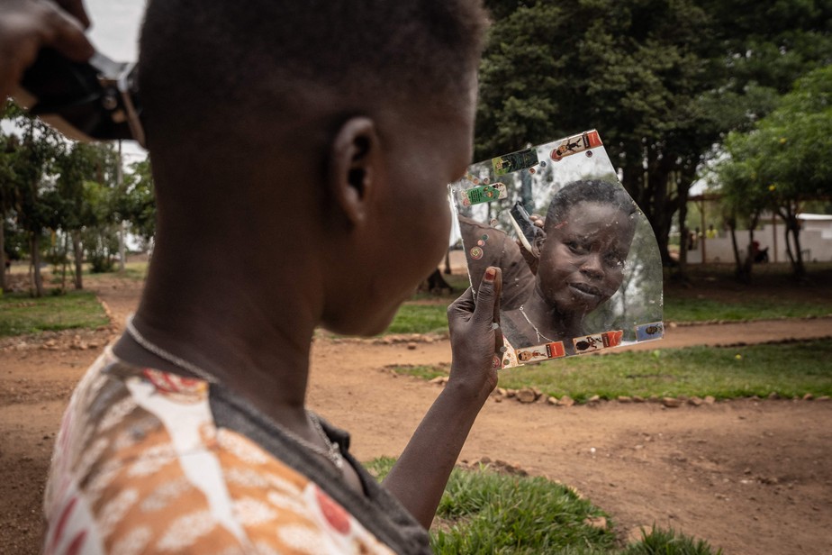 Nyalada Gatkouth Jany, uma solicitante de asilo do Sudão do Sul que tentou atravessar o Mar Mediterrâneo quatro vezes e foi presa na Líbia, corta o cabelo no Centro de Trânsito de Emergência de Gashora, em Ruanda