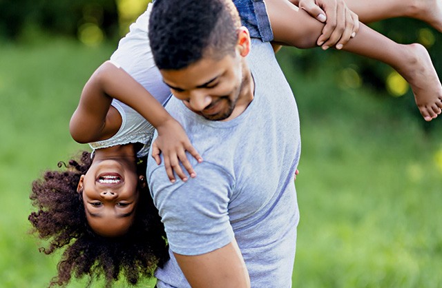 Pai e filha negros se divertem sorrindo e brincando de carregar a criança no ombro (Foto: Thinkstock)