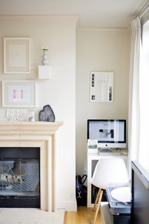 Um home office no cantinho da sala. Uma cadeira estilosa faz com que o espaço seja simples, mas estiloso.
