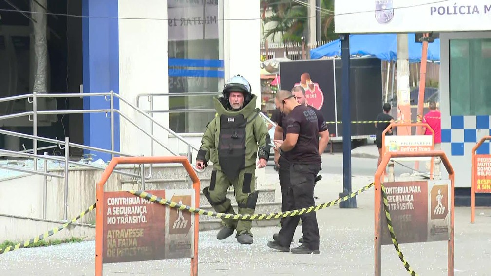 Agente do Esquadrão Antibombas tentam localizar um explosivo que teria sido deixado por bandidos durante um roubo em uma agência da Caixa Econômico de Belford Roxo — Foto: Reprodução / TV Globo