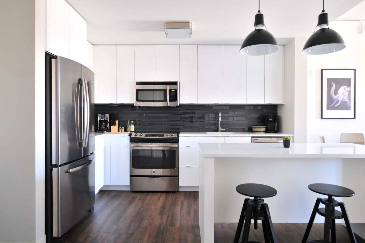 Mesmo com o revestimento preto na parede da pia, essa cozinha faz o uso da marcenaria e bancada em branco, permitindo a sensação de amplitude no espaço (Foto: Unsplash / Naomi Hébert / CreativeCommons)