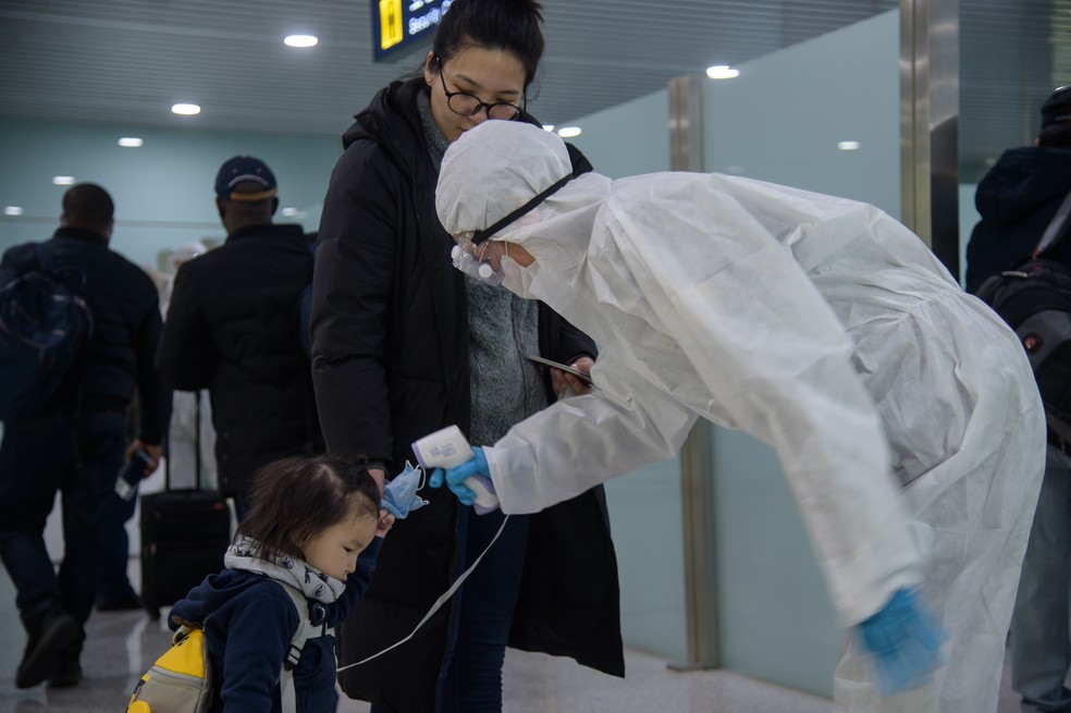 Uma criança tem sua temperatura medida enquanto diplomatas estrangeiros e funcionários da embaixada se preparam para embarcar em um voo para Vladivostok no Aeroporto Internacional de Pyongyang em 9 de março de 2020. — Foto: Kim Won Jin/AFP