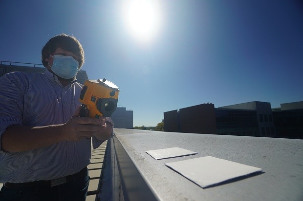 Os pesquisadores Xiulin Ruan e Joseph Peoples usam uma câmera infravermelha para comparar o desempenho de resfriamento de amostras de tinta branca em um telhado (Foto: Purdue University photo/Jared Pike)