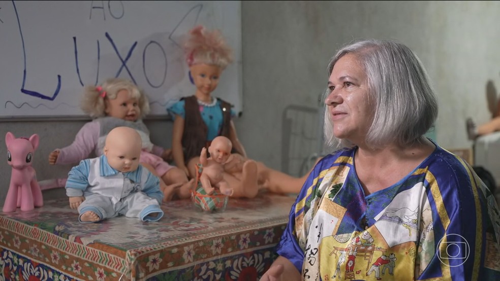 Marizete Saldanha Mello ao lado de bonecas resgatadas do rio — Foto: Reprodução/Jornal Nacional