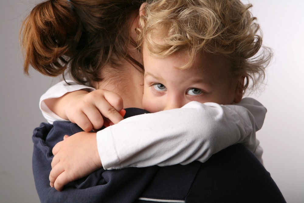 Criança triste no colo da mãe (Foto: Shutterstock)