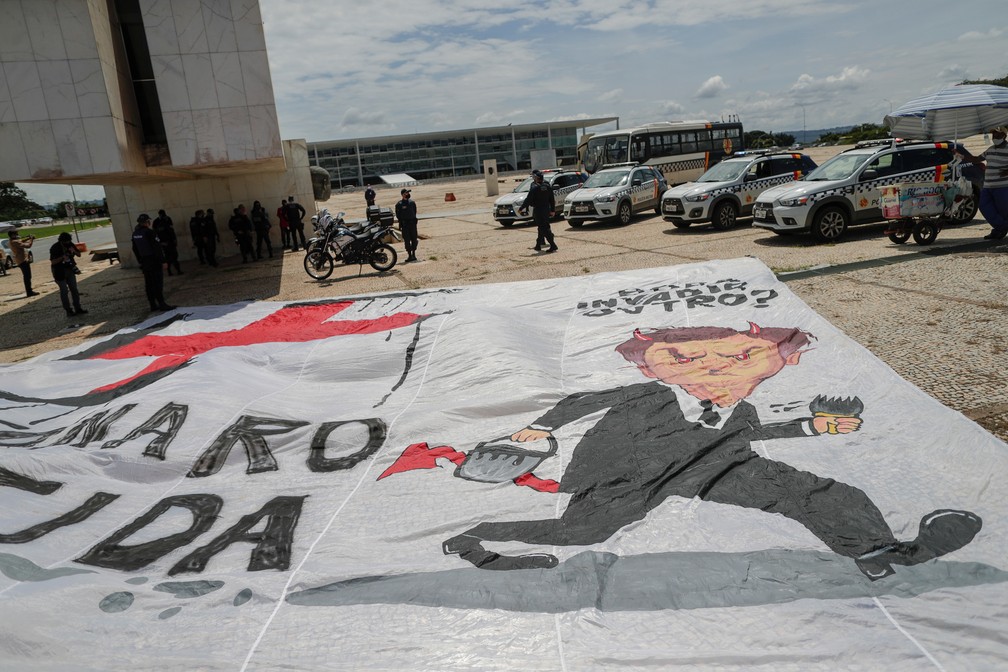 Grupo estende faixa contra presidente Jair Bolsonaro na Praça dos Três Poderes, em Brasília, nesta quinta-feira (18). — Foto: REUTERS/Ueslei Marcelino