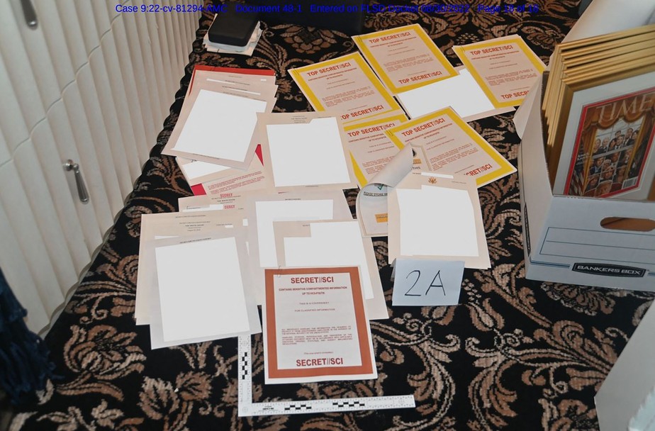Imagem mostra foto anexada como prova a um processo judicial, de documentos supostamente apreendidos em Mar-a-Lago espalhados sobre um carpete