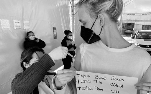 Carol Trentini leva cartaz com nome de Paulo Gustavo ao tomar vacina contra Covid-19
