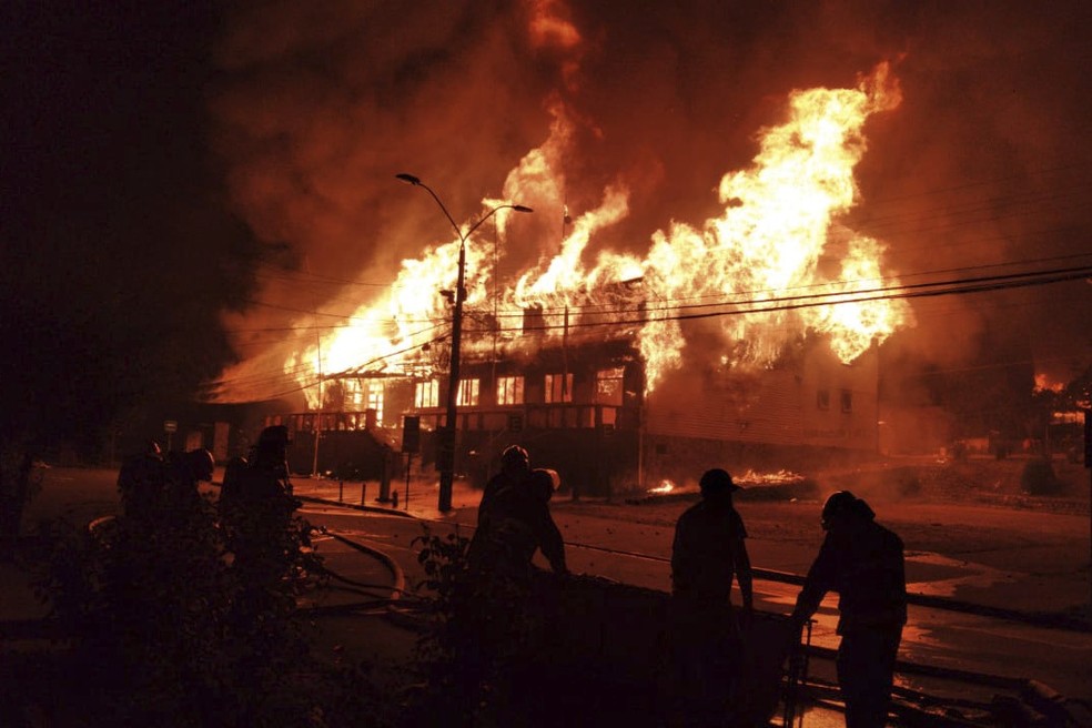Bombeiros tentam apagar fogo em prédio após protestos no Chile por morte de artista de rua — Foto: Alicia Caceres/Aton Chile via AP