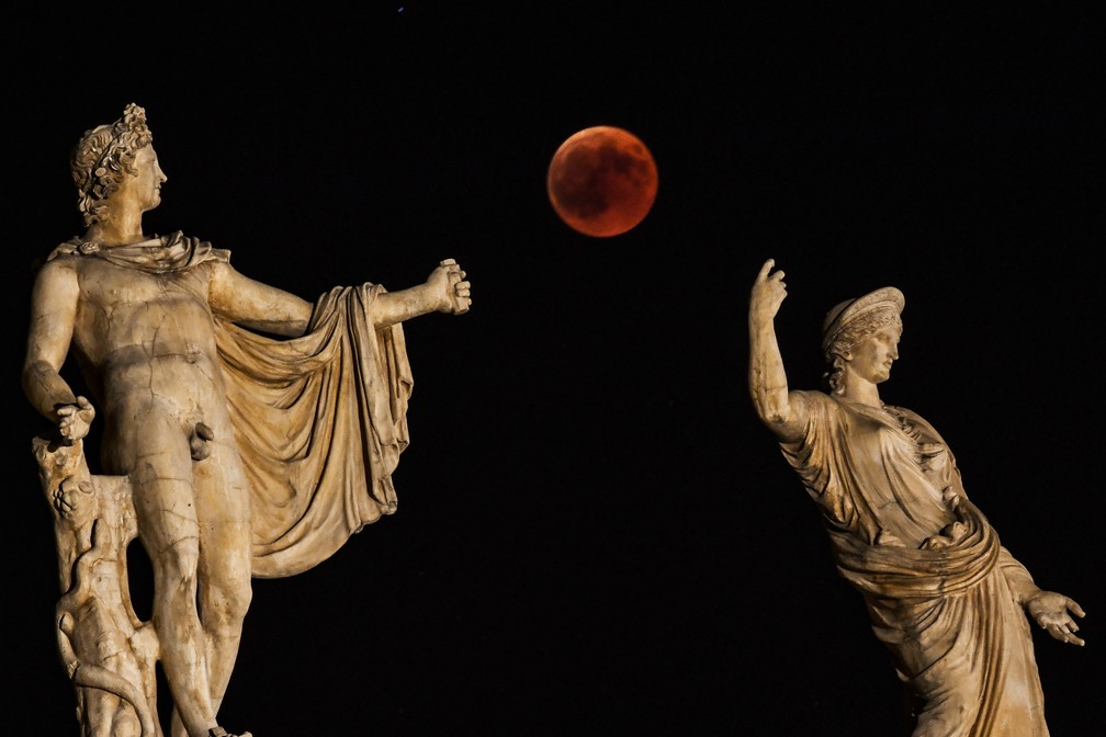 Eclipse da Lua de Sangue visto entre as estátuas de Hera e Apolo em Atenas, na Grécia (Foto: Aris MESSINIS/AFP)