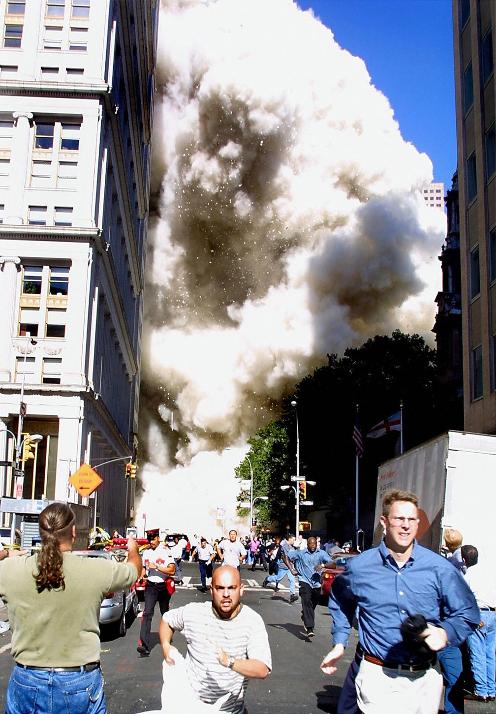 Pedestres correm enquanto uma das torres do World Trade Center vem abaixo e uma nuvem de poeira e destroços se aproxima em Nova York, no dia 11 de setembro de 2001 — Foto: Doug Kanter/AFP/Arquivo