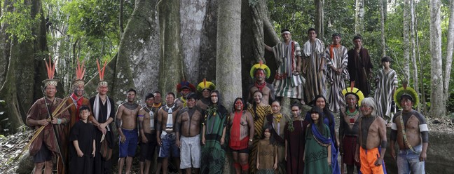 Indígenas ashaninka posam com seus parentes kayapós aos pés de uma sumaúma, árvore sagrada da foresta — Foto: Domingos Peixoto / Agência O Globo