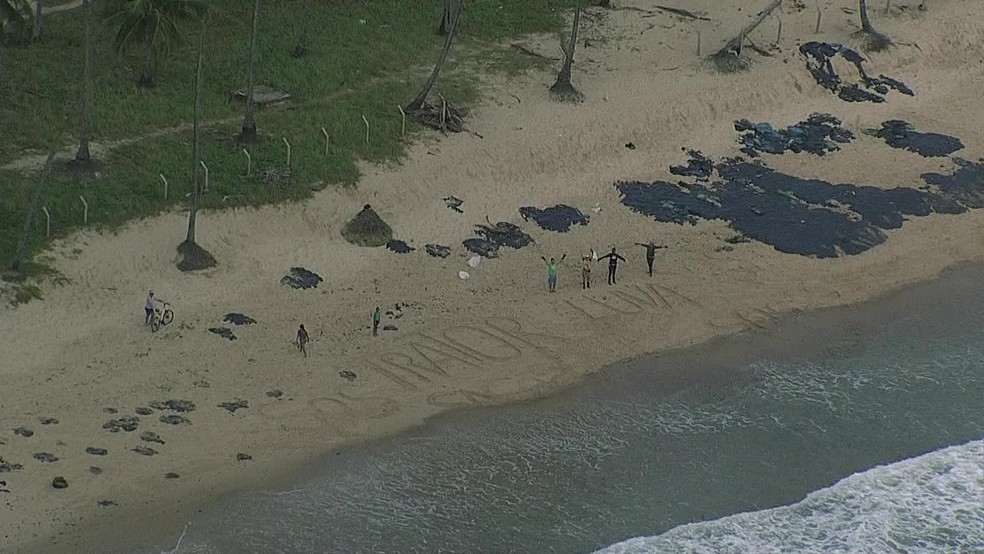 Voluntários escrevem na areia para pedir luvas e trator para retirar manchas de óleo da praia de Itapuama, no Cabo de Santo Agostinho, no Grande Recife, nesta segunda-feira (21) — Foto: Reprodução/TV Globo