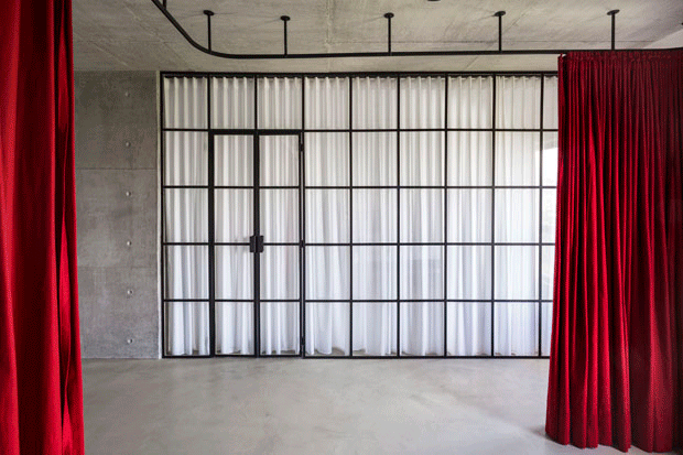 Cortinas vermelhas e vidros separam ambientes em apartamento industrial (Foto: Ricardo Jaeger/Divulgação)