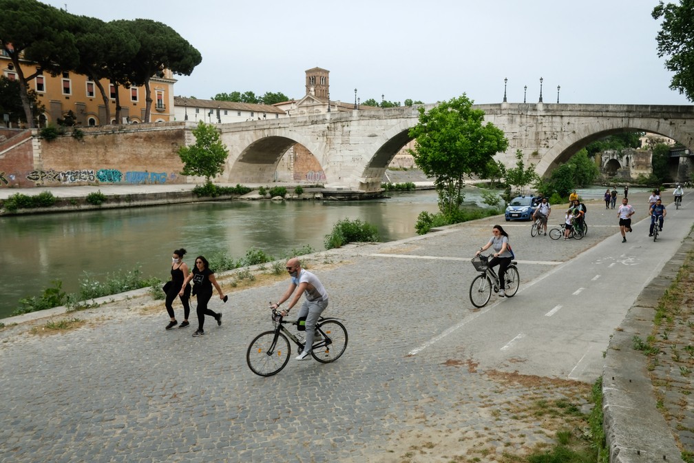 Pessoas andam de bicicleta em uma ciclovia ao longo do rio Tibre no centro de Roma, na Itália, durante o bloqueio do país com o objetivo de conter a propagação da infecção por COVID-19 — Foto: Andreas Solaro/AFP