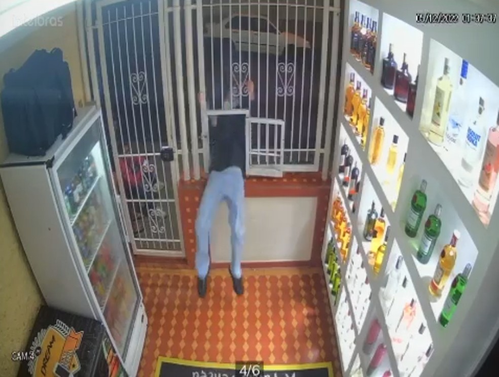 Homem passa por pequena abertura em grade e assalta loja de bebidas no interior de SP; vídeo — Foto: Câmera de segurança/Reprodução