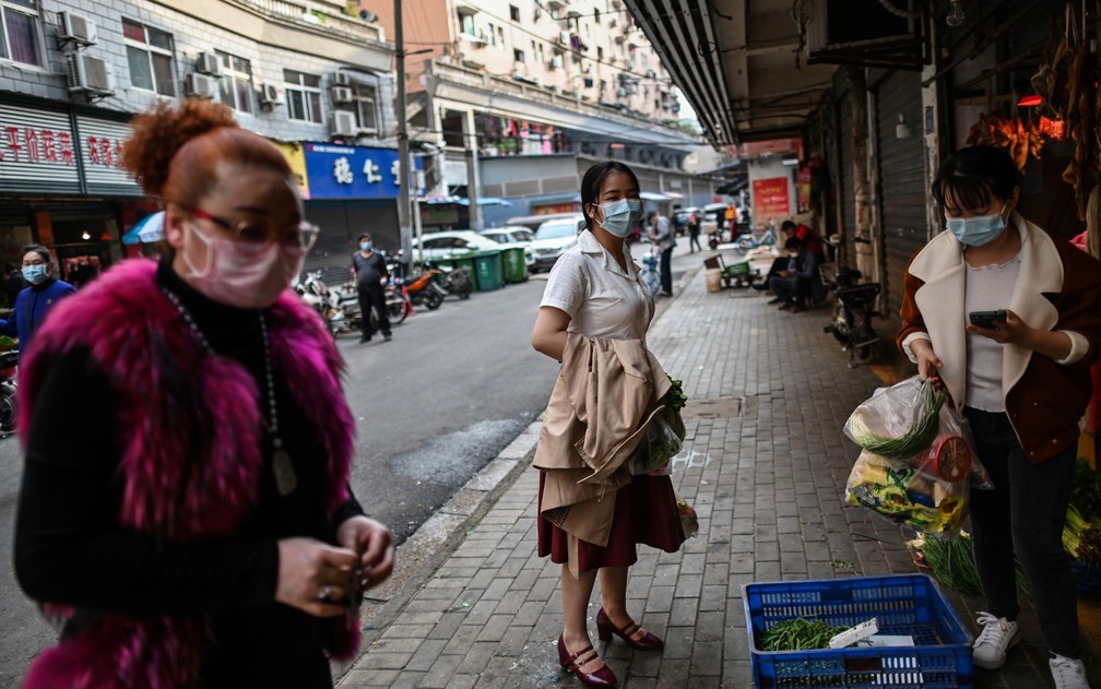 Usando máscaras, mulheres fazem compras em Wuhan, após o fim da quarentena na província de Hubei, na China, na quarta-feira (8) — Foto: Hector Retamal/AFP 