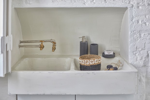 Detalhe da cuba do banheiro, com torneiras rústicas e parede de tijolinhos brancos 