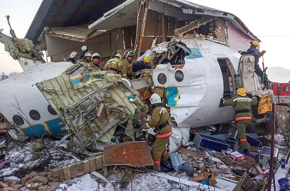 Aeronave partiu-se em duas partes ao colidir com um muro de concreto e uma casa — Foto: HO / Kazakhstan's emergencies committee / AFP