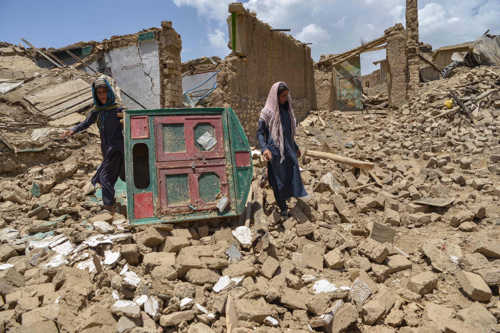 Homens afegãos procuram  pertences em meio às ruínas de uma casa danificada por um terremoto no distrito de Bernal, província de Paktika  — Foto: SAHEL ARMAN / AFP