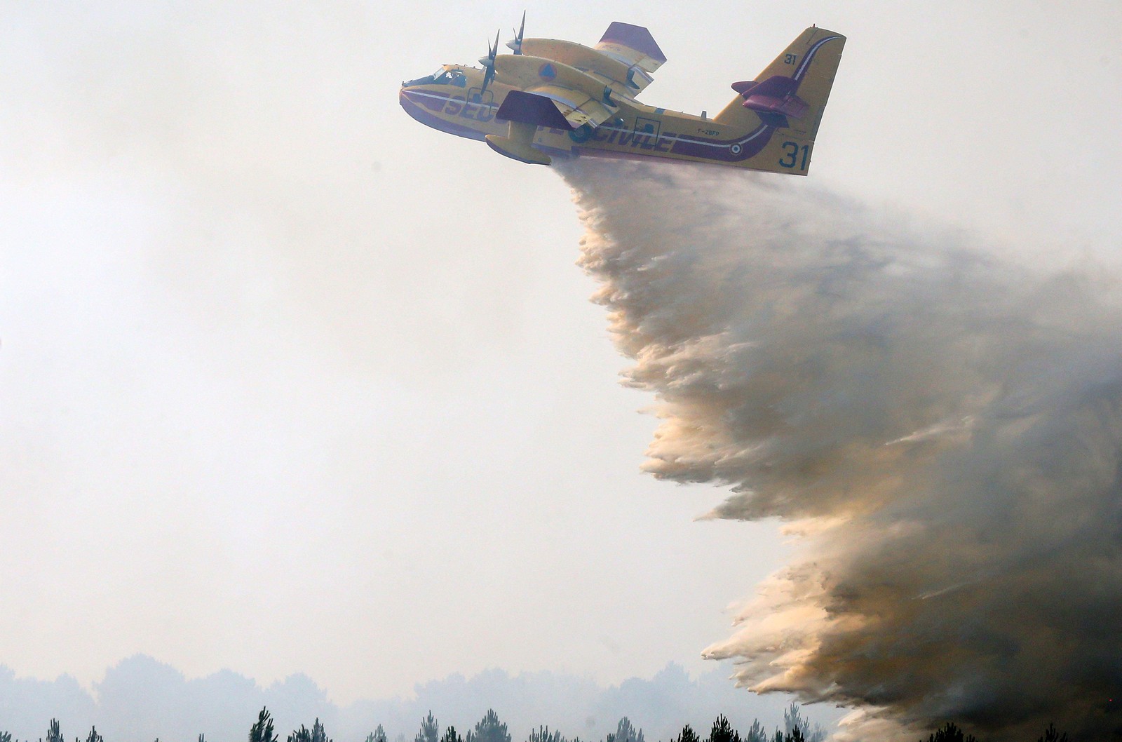 Avião de combate a incêndios  despeja água sobre um foco em Landiras, sudoeste da França, onde mais de  6 mil camponeses foram deslocados — Foto: LAURENT THEILLET / AFP