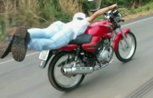 Homem é flagrado deitado sobre tanque da moto em movimento em Goiás (Foto: Reprodução/TV Anhanguera)