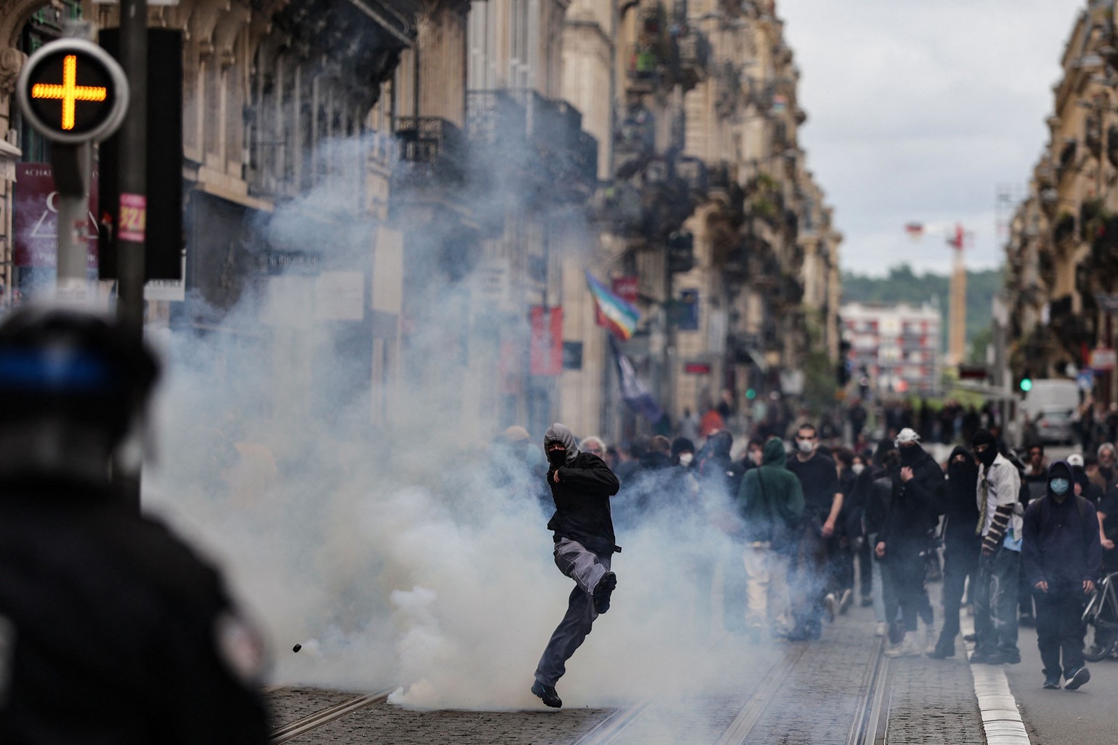 Manifestante chuta uma bomba de gás lacrimogêneo de volta para a polícia durante confronto em Bordéus, sudoeste de França — Foto: Thibaud MORITZ / AFP