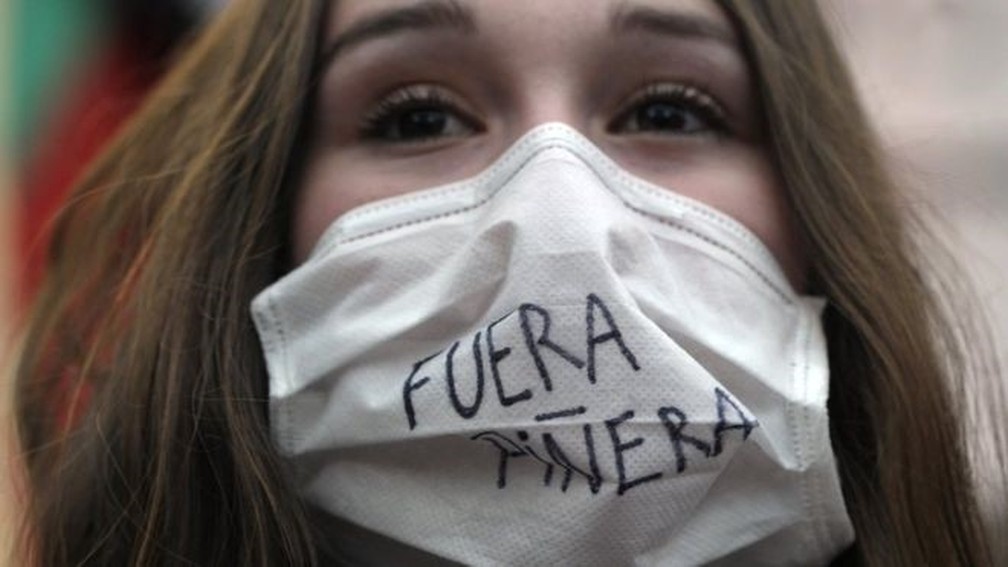 Manifestante usa máscara com dizeres: 'Fuera Piñera'. O sistema de saúde é precário para muitos chilenos — Foto: Getty Images via BBC