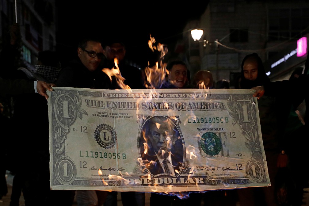 Manifestante queima nota falsa de dólar com rosto de Donald Trump em Ramallah, na Cisjordânia, nesta terça-feira (28) — Foto: Mohamad Torokman/Reuters