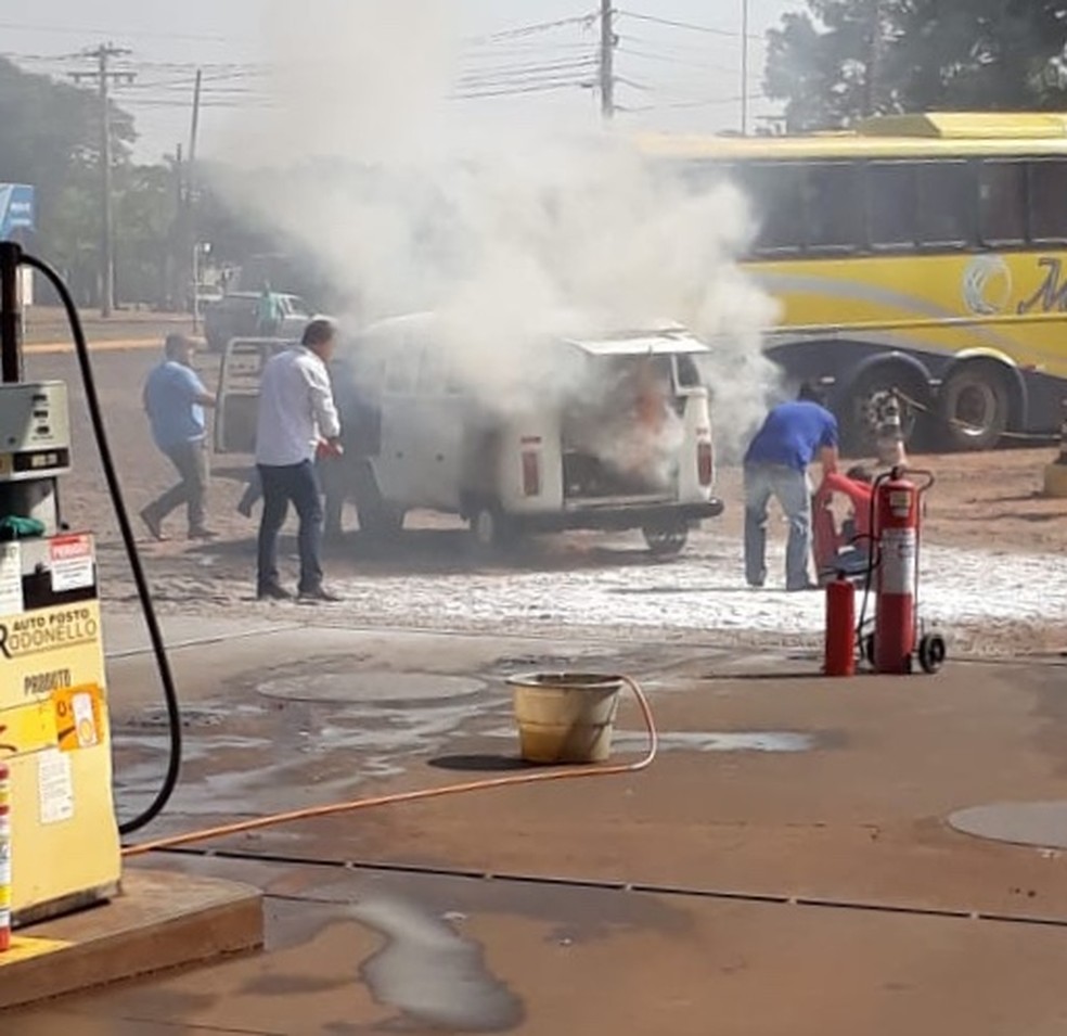 Funcionários de posto de combustível empurra kombi que pegou fogo. — Foto: Rafael Chiovetti