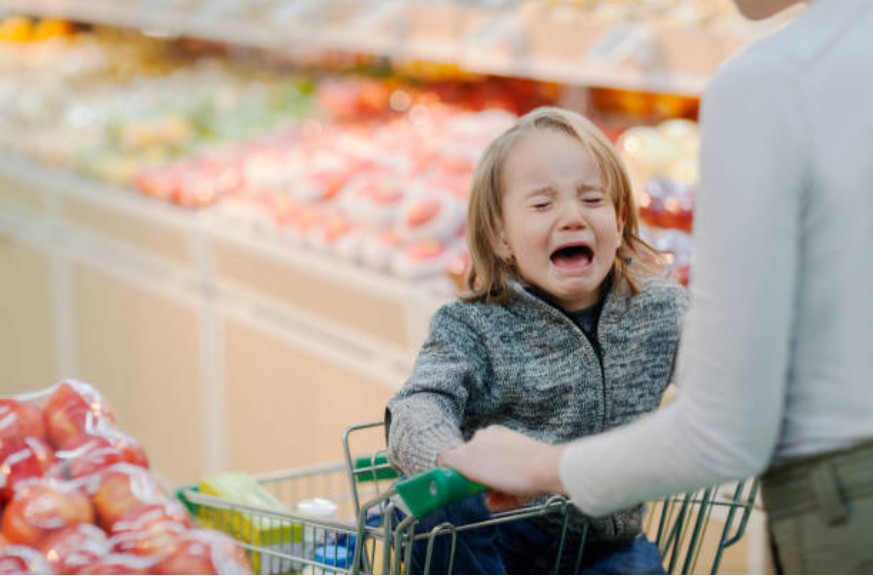 Criança acompanhada da mãe chorando em carrinho de supermercado (Foto: Getty Images)