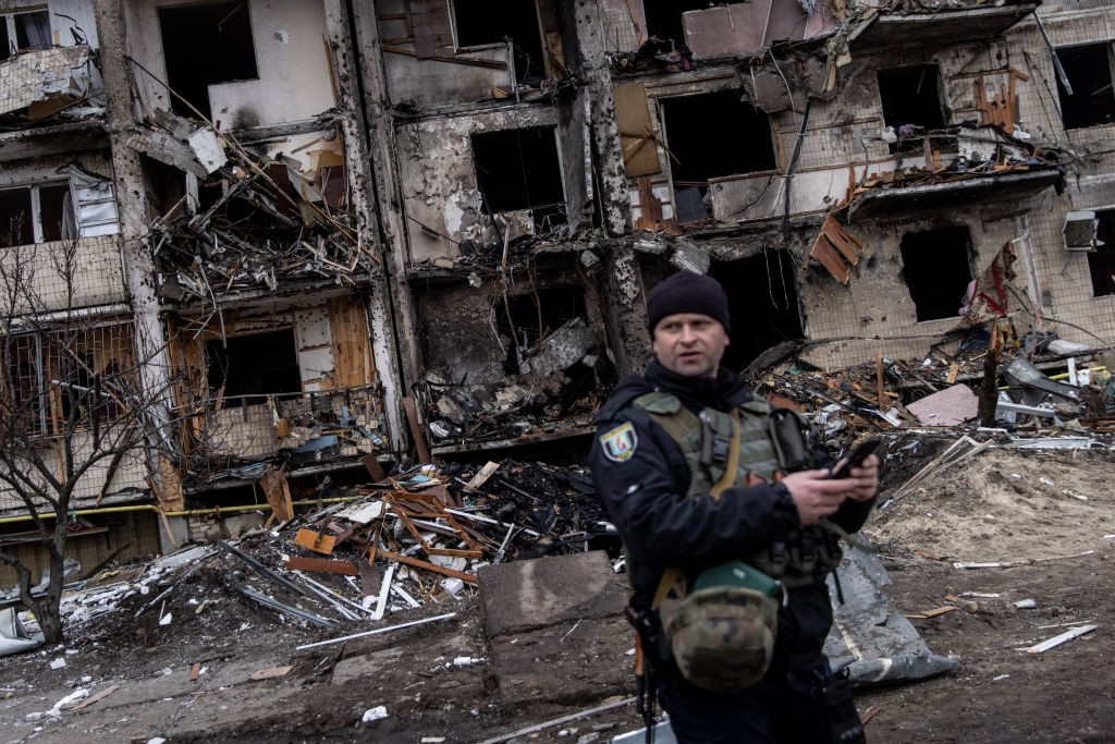 Policial ucraniano em frente a bloco residencial atingido por um ataque de mísseis russos (Foto: Getty Images)