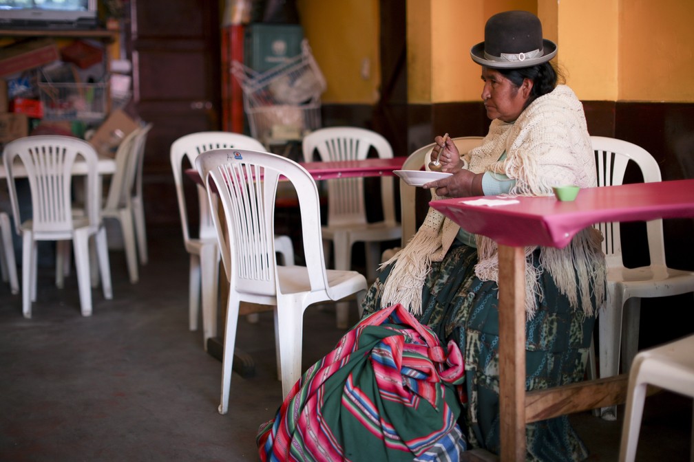 Mulher come sozinha em restaurante em La Paz, na Bolívia, nesta sexta-feira (18) — Foto: Natacha Pisarenko/AP Photo