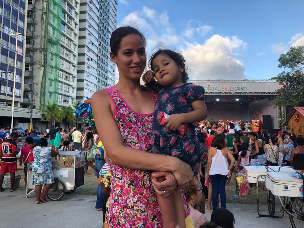 Rayza subiu num banco com a filha Manuela para ver melhor o palco do Natal Solidário, no Recife — Foto: Pedro Alves/G1